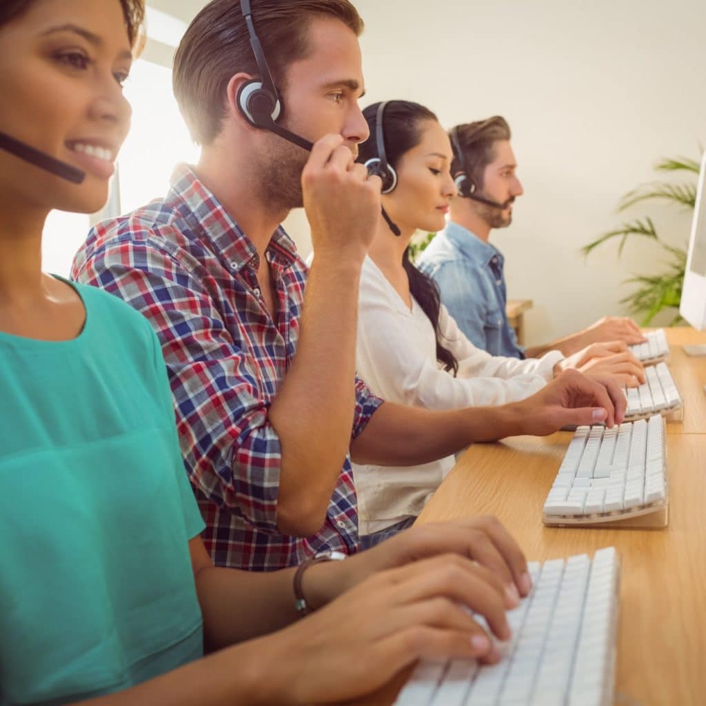 Business team working together at a call centre wearing headsets