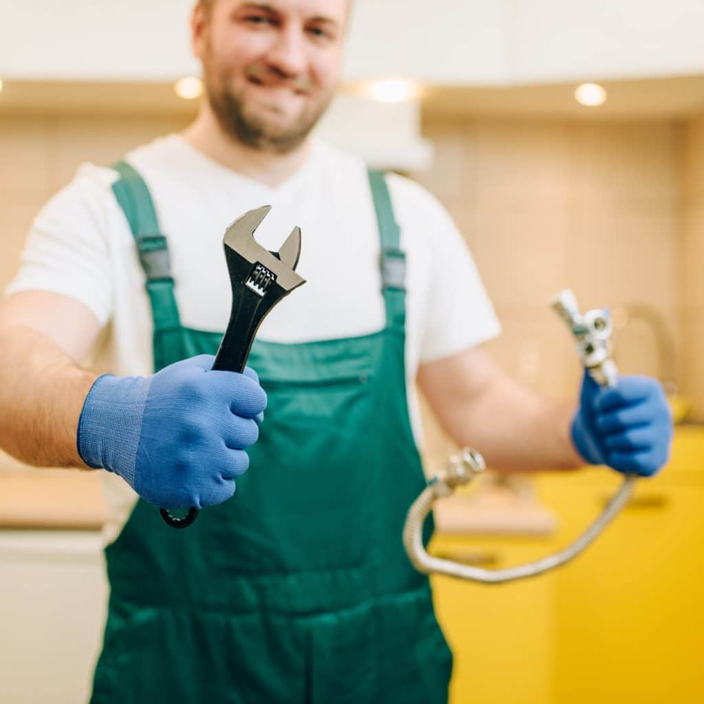 Plumber in uniform holds wrench, handyman